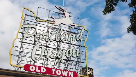 hd cartel estático del casco antiguo de portland oregon en el marco central izquierdo con la torre de agua del casco antiguo asomándose a través y fuera del cartel con el cielo parcialmente nublado