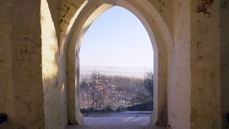 wide shot of monument archway looking out at winter heavy frost fields 4k