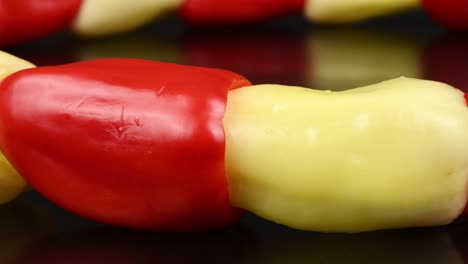 pimientos amarillos y rojos dulces en fila sobre fondo negro. primer plano extremo. concepto de alimentos saludables. preparación de verduras para ensalada. movimiento de bucle. vista lateral. rotación 360.