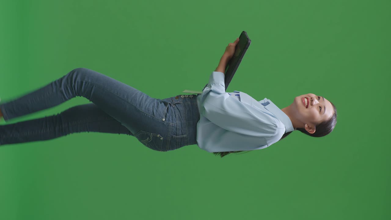 스튜디오에서 녹색 화면 배경에서 는 동안 태블릿을 사용하는 아시아 사업가의 측면 시각