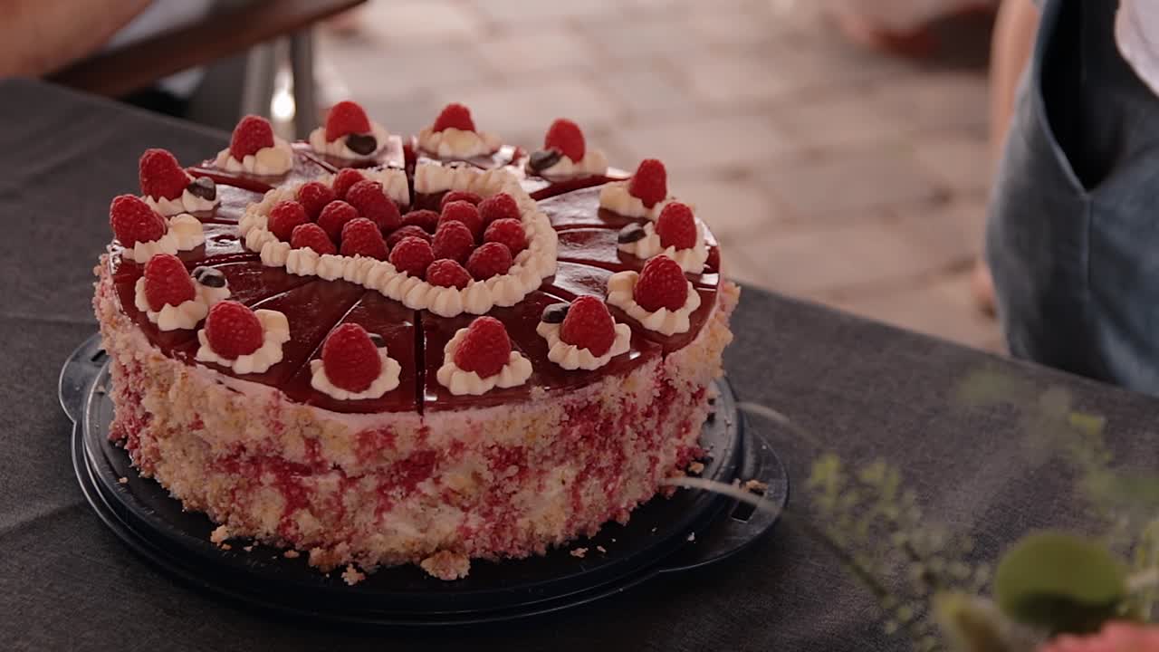una giovane donna si avvicina alla torta di lamponi che è sul tavolo