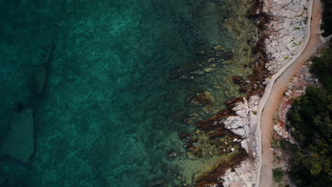 Vista-Aérea-De-Pájaro-De-La-Escarpada-Costa-Rocosa-Blanca-Que-Se-Desvanece-En-Agua-Azul-Turquesa