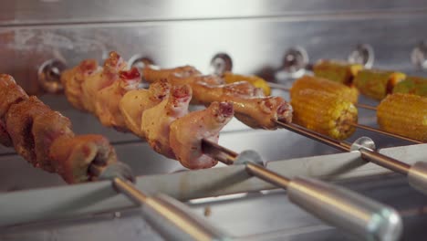 roasted chicken, corn and other meats on skewers in a rotisserie