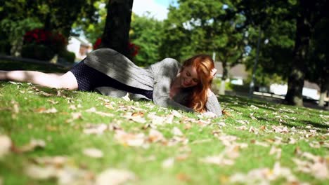 calm redhead posing lying on green lawn