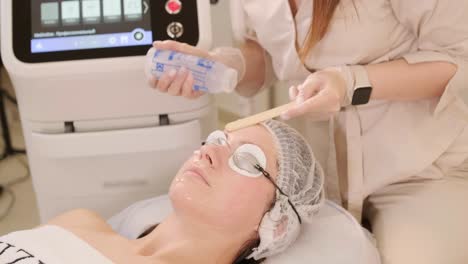 woman receiving radiofrequency lifting procedure around eyes for her face skin rejuvenation at aesthetic cosmetology center