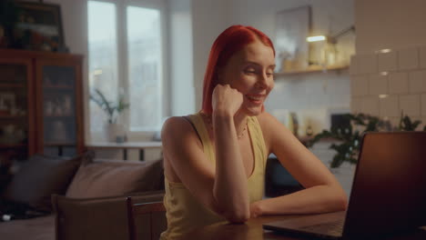 cheerful girl waving and chatting via laptop video call at home