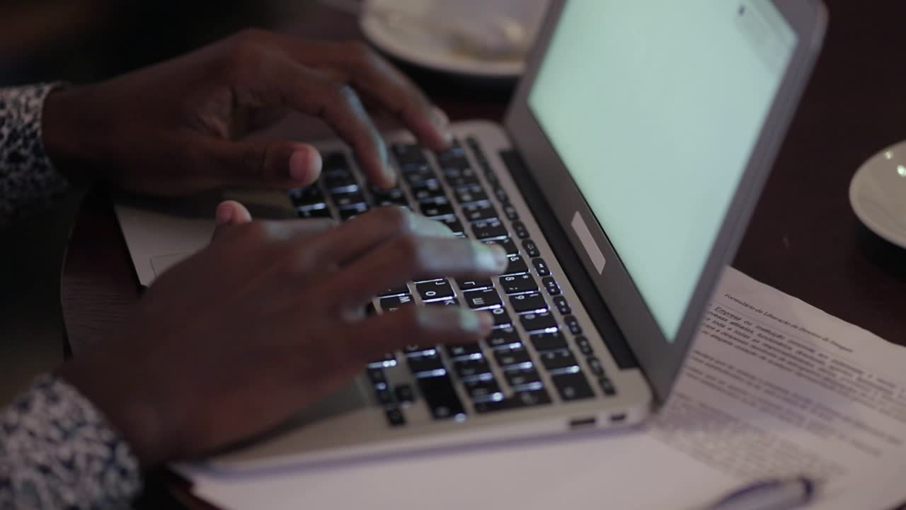 African American man typing on laptop in cafe