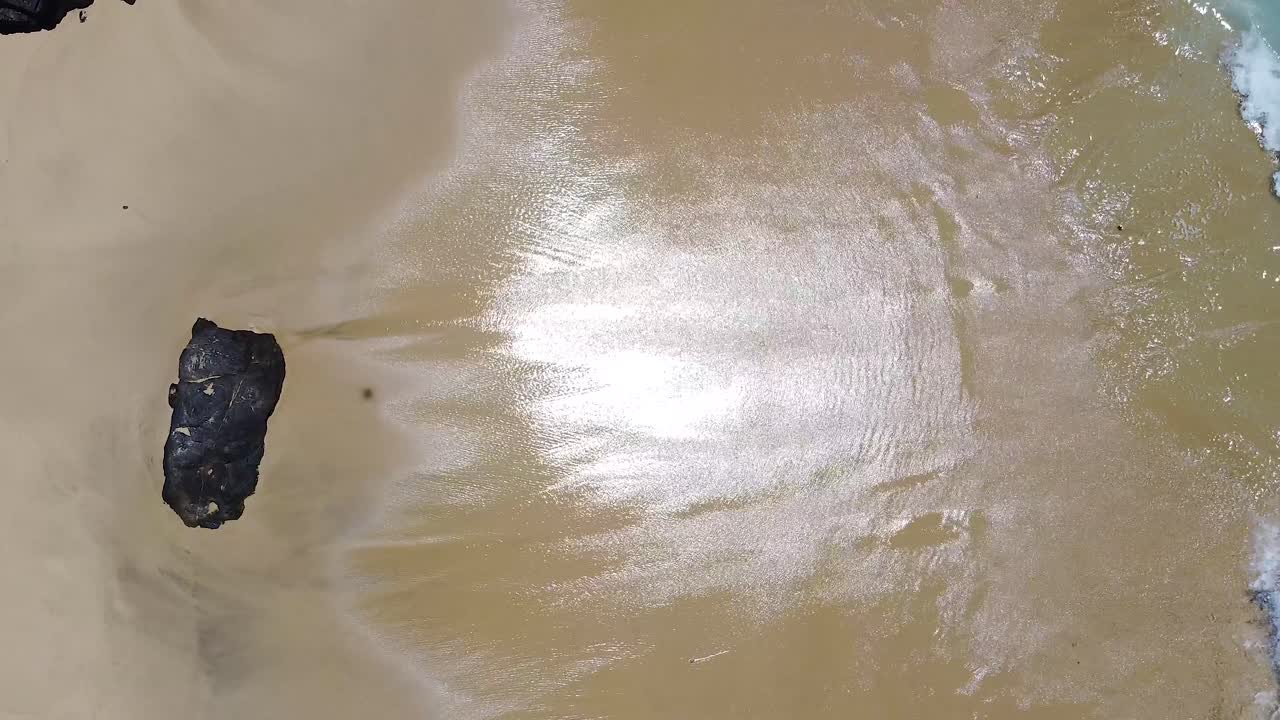 Waves breaking on white sand rocky beach during warm summer day