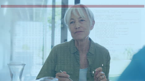 Animation-of-red-line-over-caucasian-senior-woman-talking-while-sitting-at-table-at-home