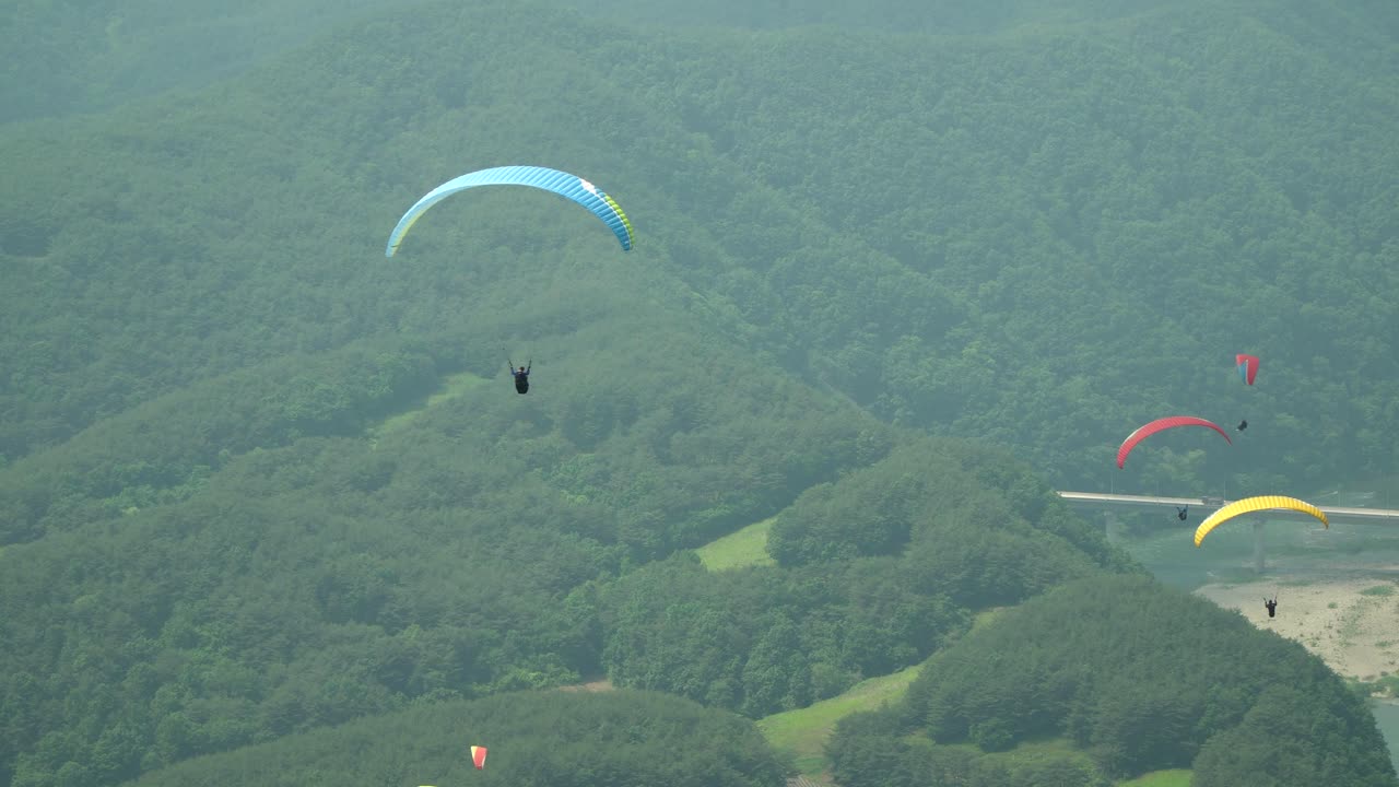 muchos parapentes en tándem deslizándose lentamente sobre el fondo de las montañas verdes en la ciudad de danyang, corea del sur