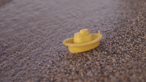 yellow toy boat on the beach 50p