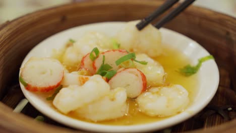 close-up of steamed shrimp and crab stick dish, chopsticks pick up piece