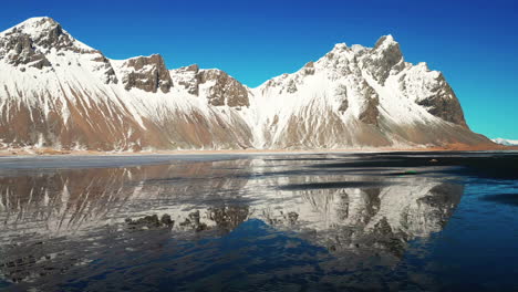 Ein-Mann,-Der-Tagsüber-In-Südisland-Vor-Dem-Berg-Vestrahorn-Mit-Perfekter-Spiegelung-Steht