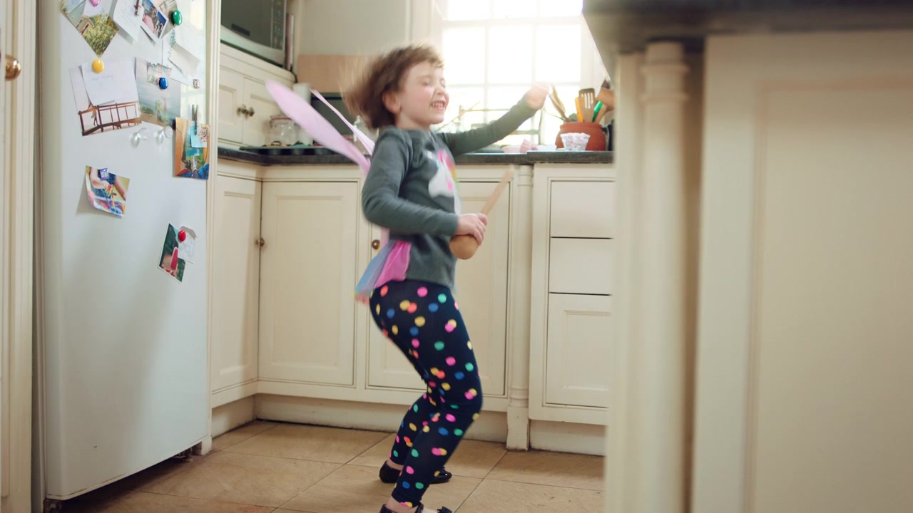 Little Girl Wearing Fairy Wings Dancing in Kitchen