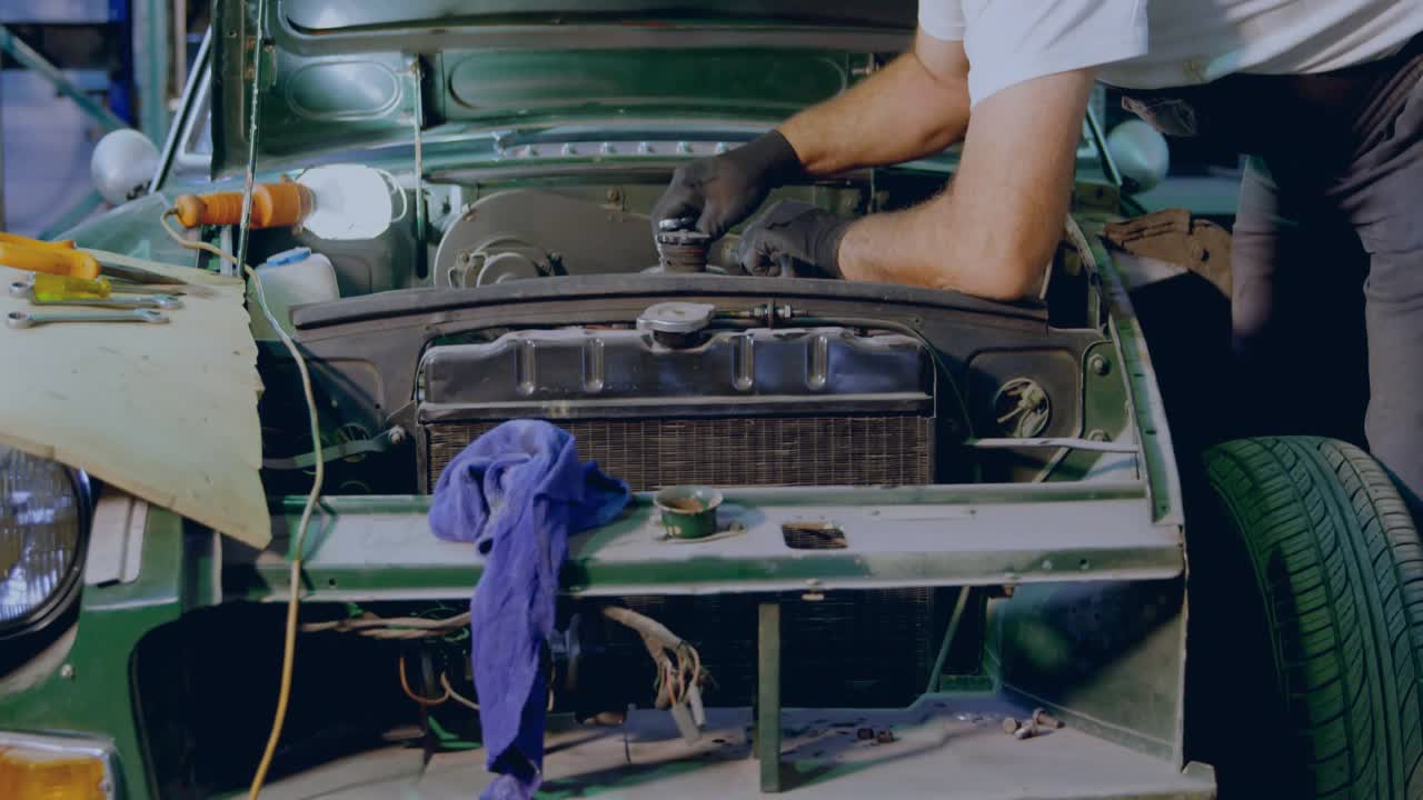 White-haired mechanic wiping radiator and then removing filter from car engine bay for maintenance