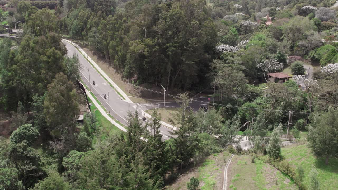 Drone view some motorbikes driving down a rural road in Colombia