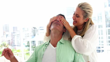 Mujer-Sonriente-Cubriendo-Los-Ojos-Del-Hombre-En-El-Salón-De-Casa