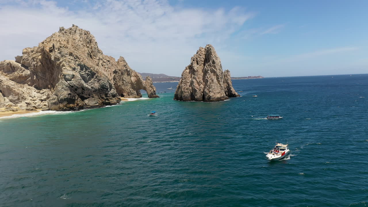 toma de drones de barcos en el océano con acantilados marinos en el fondo en cabo san lucas méxico