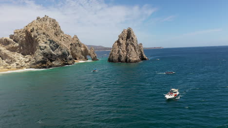 Drohnenaufnahme-Von-Booten-Im-Ozean-Mit-Meeresklippen-Im-Hintergrund-In-Cabo-San-Lucas-Mexiko