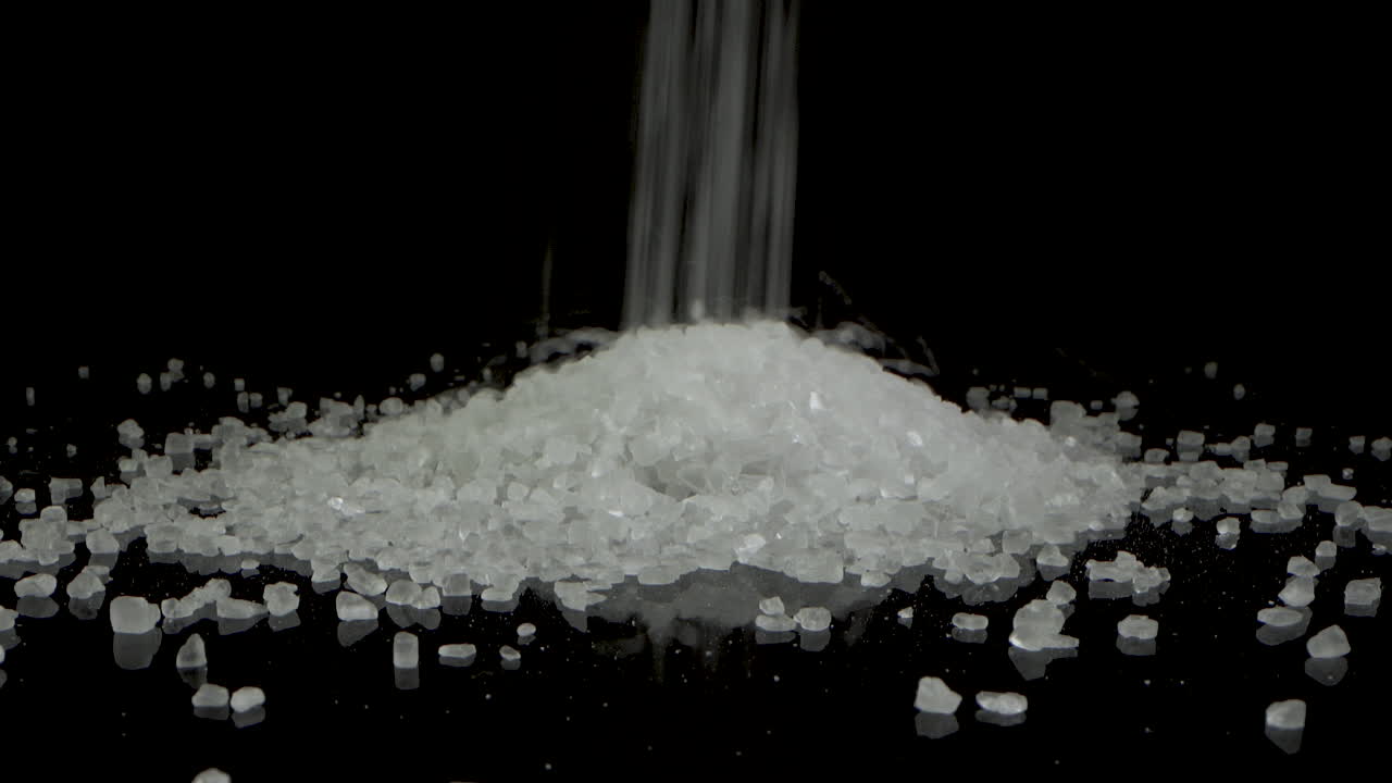 크리스탈 거친 바다 소금이 떨어지고 언덕을 만드는 검은 거울 테이블