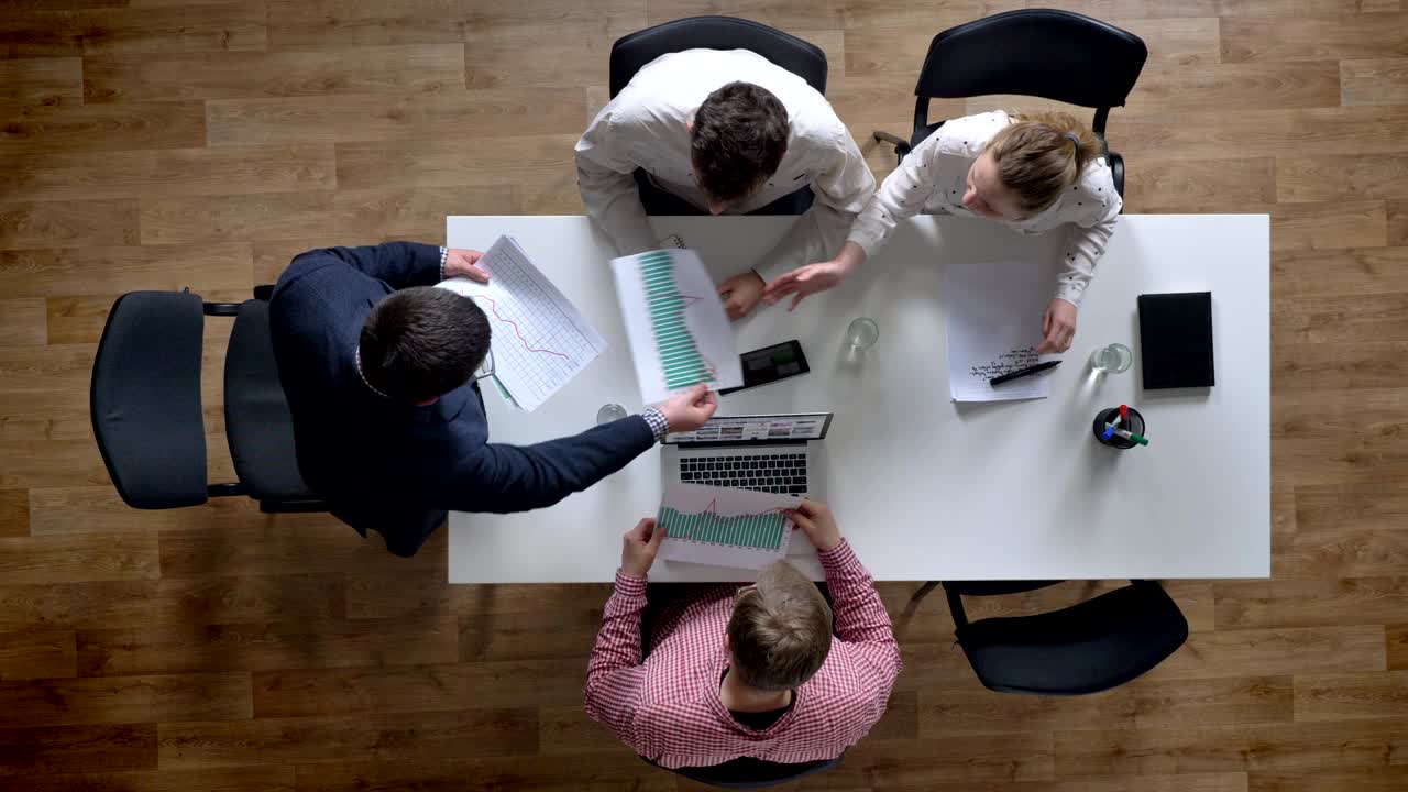 jefe entrando y dando documento a todo el mundo, topshot, equipo de negocios celebrando una reunión en una oficina moderna, sala de juntas por encima
