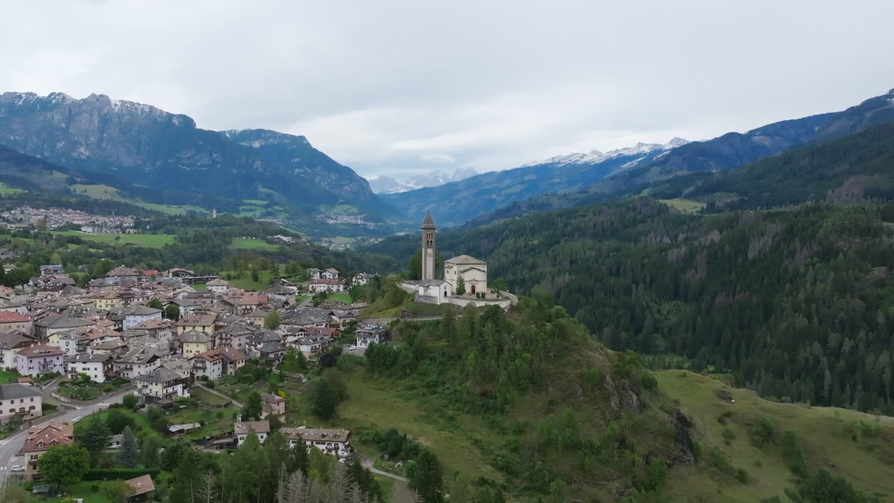 Aerial footage flying towards a church spire on a hill just outside a small Italian town.