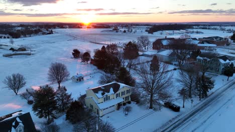 two story homes along rural country road in winter snow scene at sunrise