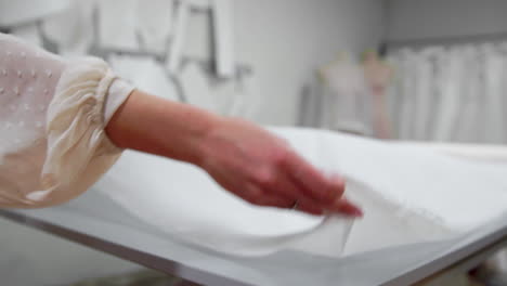 clothing designer is working with measurements on a studio table. shot on in 4k uhd . closeup deploy a skein of white fabric in white and light-colored sewing in slow motion.