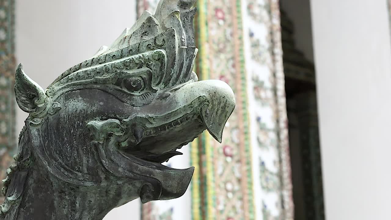 подробный вид мифической статуи в ват-фра-кейу, бангкок, демонстрирующий сложную архитектуру и культурное мастерство в естественном освещении