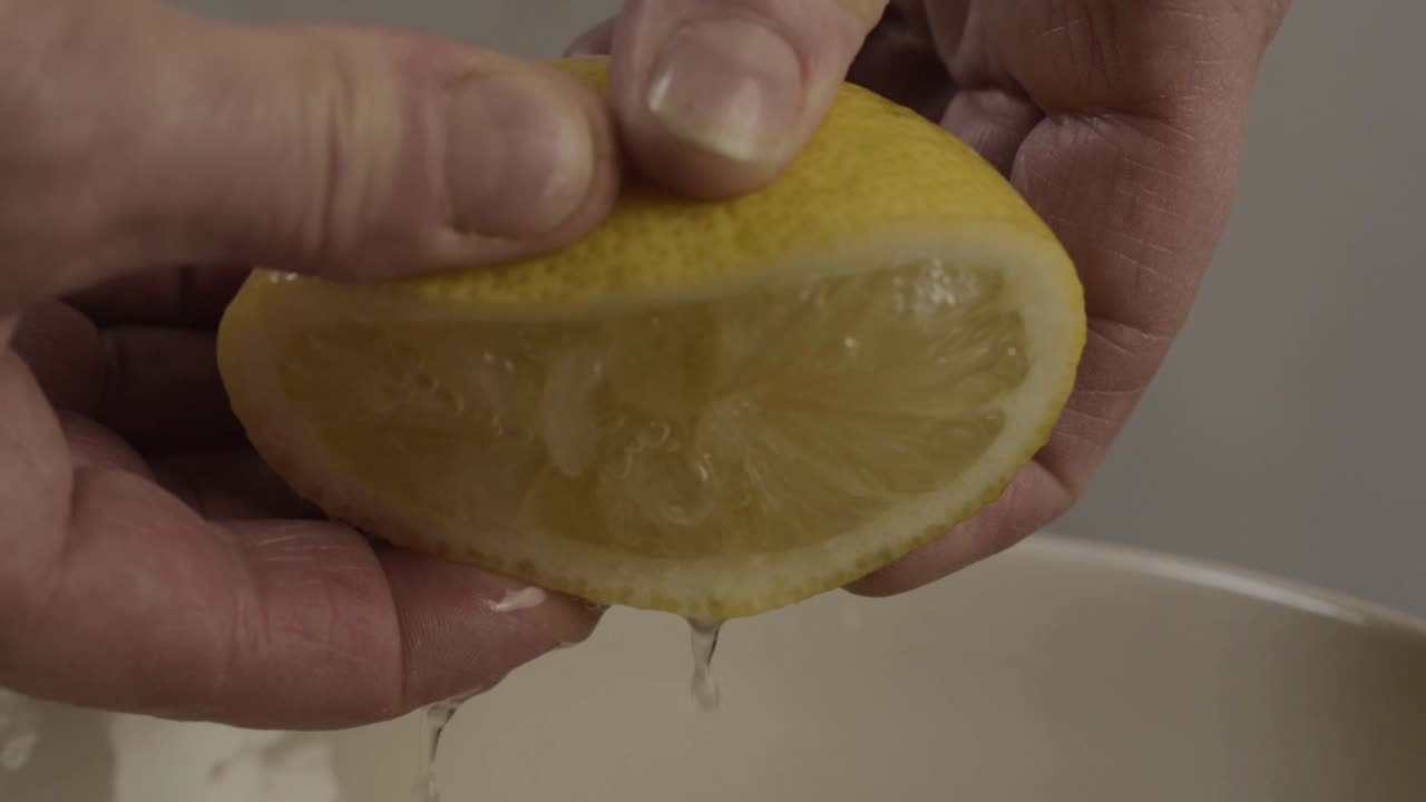 Hand squeezing juicy lemon close up shot