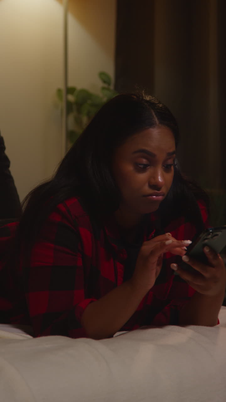 Woman using phone in bed at night