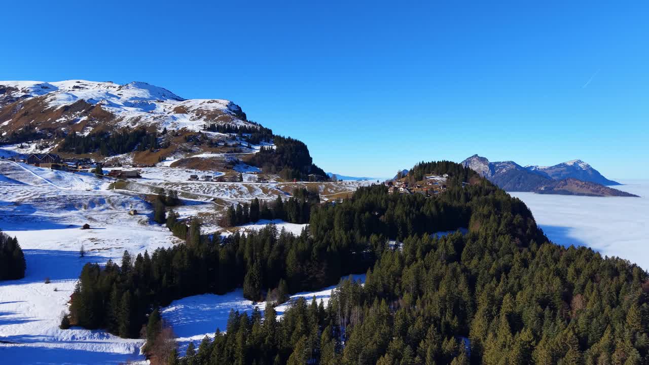 Filmato aereo che sorvola un terreno alpino innevato con pini verdi in una giornata invernale soleggiata nella regione di Stoos Muotathal