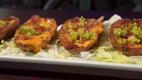 loaded potato skins on a lettuce lined tray, slider close up hd