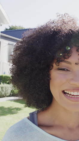 vertical video of portrait of happy biracial woman smiling in garden, slow motion