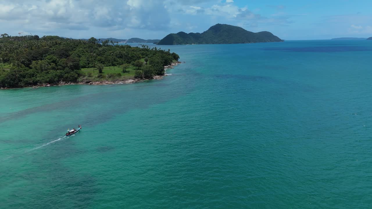 Drone orbits a longtail boat heading into the Andaman off and Rawai Beach, Phuket