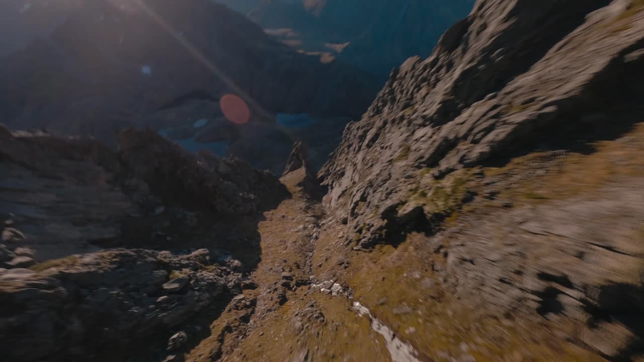 Volo aereo in discesa tra le montagne rocciose verso un fiordo in Norvegia - Ripresa dinamica con drone FPV in estate