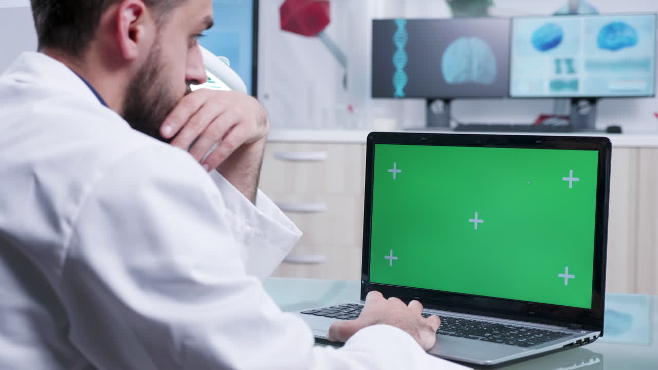 Doctor using laptop with green screen in medical office