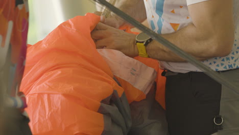 close-up slow motion of caucasian male with strong arms setting up parachute before sky dive