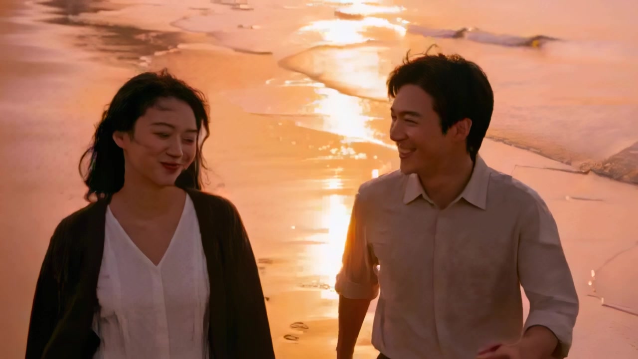 カジュアルな服装のカップルが、足跡の残る濡れた砂浜を歩いている。女性が話しかけ、男性が振り返って微笑む。