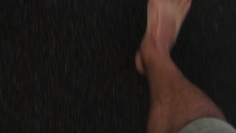 Close-up-of-feet,-walking-barefoot-on-a-black-sand-beach-with-waves-occasionally-hitting-the-feet