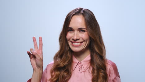 Businesswoman-showing-v-sign-in-studio.-Woman-showing-peace-sign