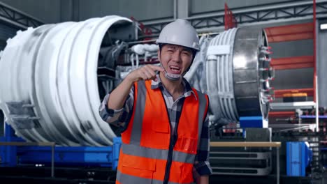 angry asian male engineer with safety helmet shouting at someone while standing with airplane engine maintenance conducted, analytics checking the turbine