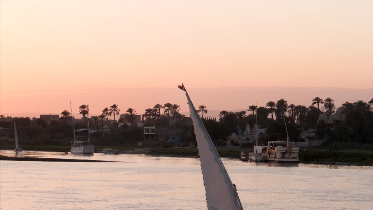 Egyptian flag on top of a felucca during sunrise on the Nile river, Luxor, Egypt.