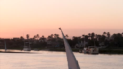 egyptian flag on top of a felucca during sunrise on the nile river, luxor, egypt.
