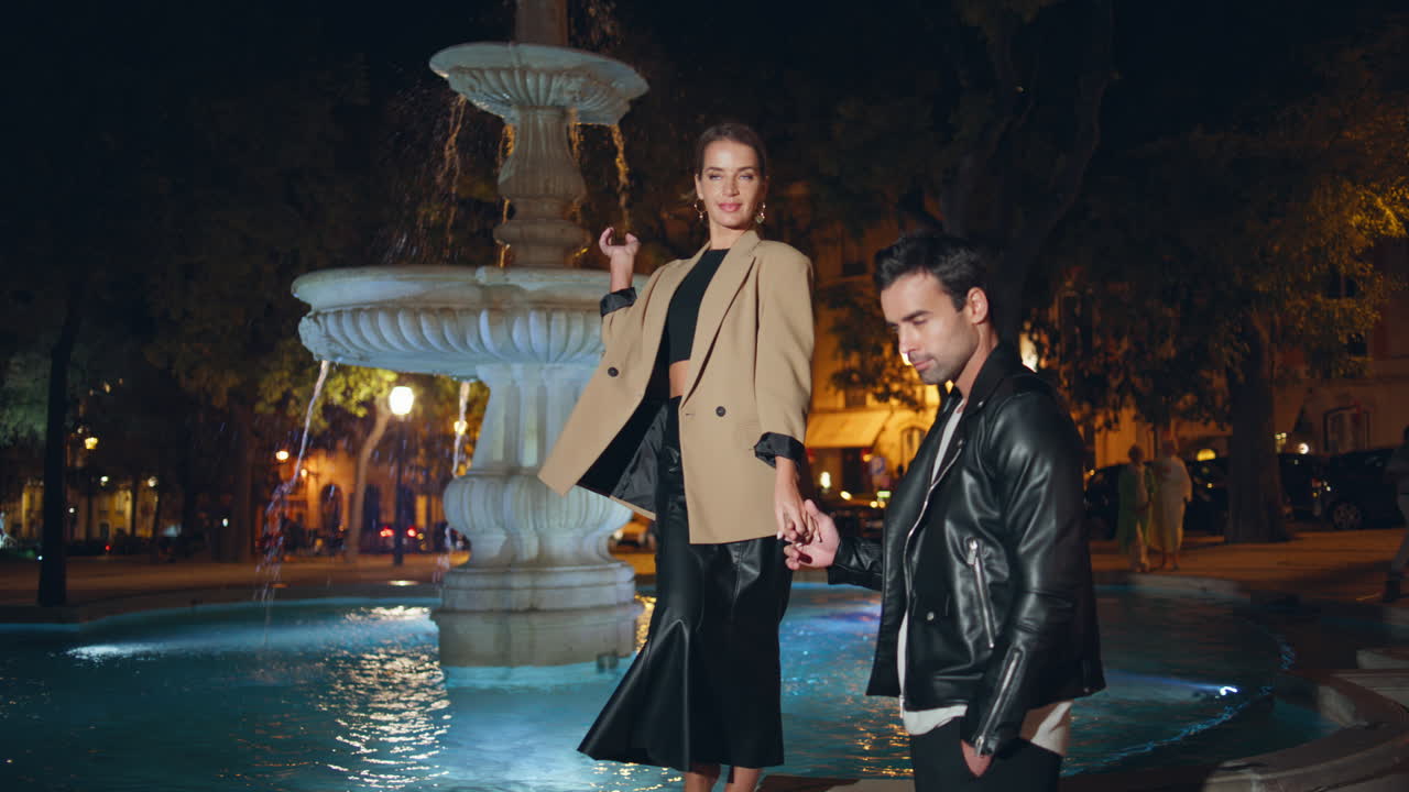 Beautiful couple holding hands on night street zoom on. Fashion trendy models