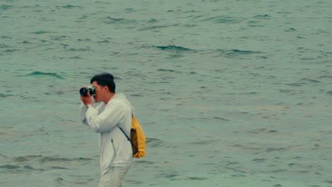 man taking pictures by the sea