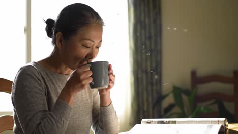 a moment of tranquility: a woman enjoys a warm beverage while reading a newspaper in a sunlit room, reflecting the calmness of a quiet morning