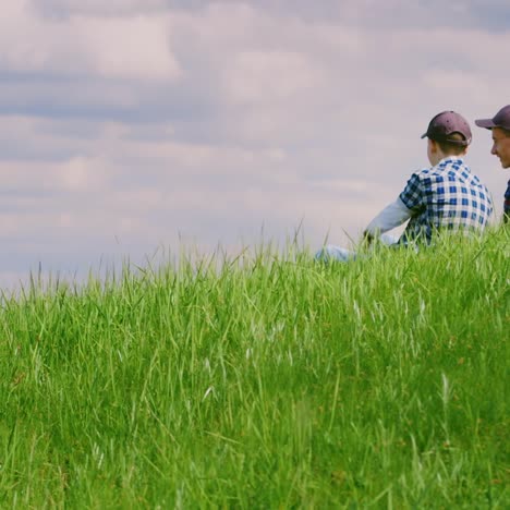 Zwei-Jungs-Im-Teenageralter-Sitzen-Auf-Einer-Grünen-Wiese