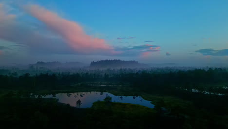 A-stunning-and-highly-cinematic-view-of-a-landscape,-featuring-lush-green-forests,-lakes,-and-hills-enveloped-in-clouds-and-fog,-resembles-a-scene-from-a-movie