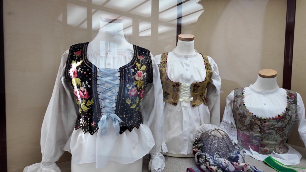 Exposición de museo de tres corsés tradicionales ornamentados con patrones florales, bordados e inspirados en la naturaleza en un entorno histórico.